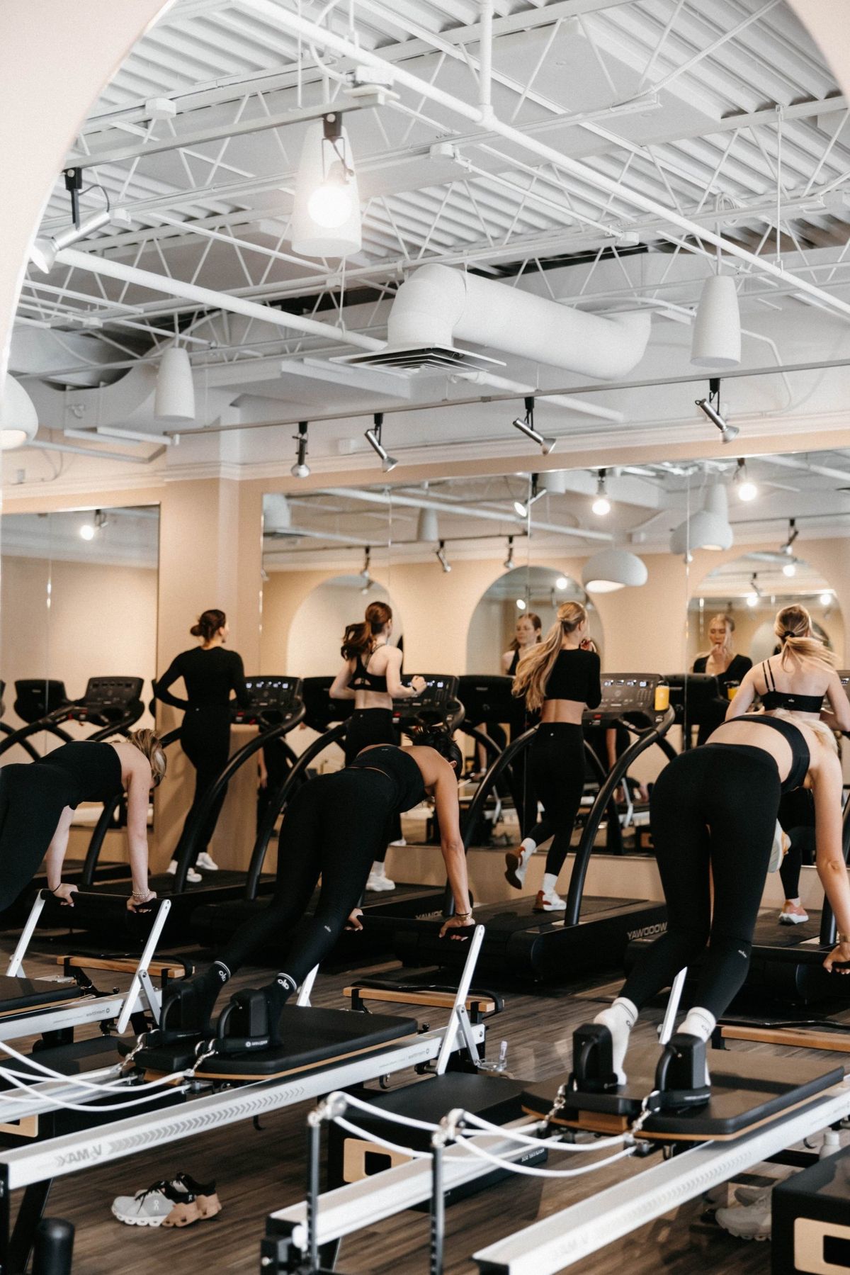 A full Rêve class in session — reformers and treadmills arranged beneath the studio's tall arched window